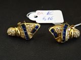 paire de boucles d'oreilles bleues et dorées ornées de diamants sur un fond noir
