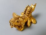 a gold figurine of a fish with a crown on its head