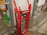 a red hand truck that is sitting in front of a fence