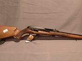 un fusil et une chaussure sont posés sur une table à fond blanc