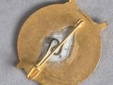 an image of a gold brooch with a pin in the middle