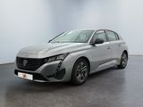 Une voiture argentée est garée dans une pièce aux murs blancs.