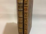 two old books sitting on top of each other on a white surface