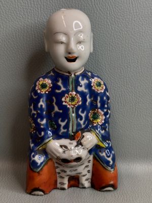 une figurine représentant un homme assis sur un tabouret avec un chat