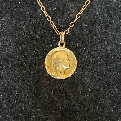 a gold coin necklace with a woman ' s face on it