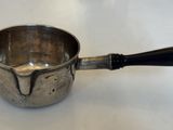 une tasse en argent avec une anse noire posée sur une table blanche