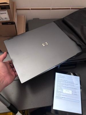 Quelqu'un tient un ordinateur portable et un téléphone portable posés sur une table.