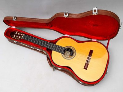 une guitare dans un étui, posée sur une surface blanche