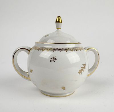 a white teapot with a gold decoration on it