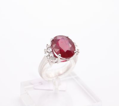 a close up of a ring with a red stone surrounded by diamonds