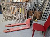a red chair sitting next to a stack of pallets in a garage