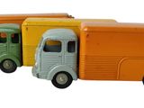 trois camions miniatures alignés les uns à côté des autres sur une surface blanche