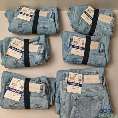 cinq paires de jeans bleus sont disposées sur une table