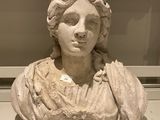 marble bust of a woman with curly hair in a glass case