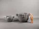 two cement mortars and a wooden hand on a gray background