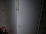 a white refrigerator and a red crate in a dark room