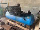 un compresseur d'air bleu posé sur une palette dans un garage