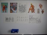 de nombreux tableaux accrochés au mur d'une pièce où se trouve une chaise bleue
