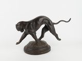 bronze statue of a dog running on a pedestal on a white background