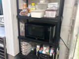a black shelf with a microwave on top of it