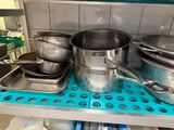 several pots and pans are on a shelf in a kitchen