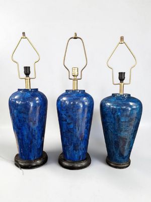 three blue vases are lined up against a white background