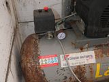 a small air compressor sitting on the ground next to a wall