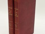 two red books sitting on top of each other on a white surface