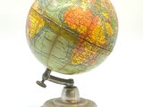 un petit globe posé sur un socle, sur une surface blanche