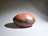 a brown leather football on a white surface