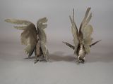 two silver figurines of birds on a white surface