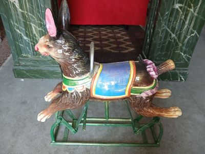 un cheval à bascule avec un lapin dessus, devant une porte rouge
