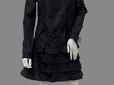 a mannequin wearing a black dress and coat with ruffles