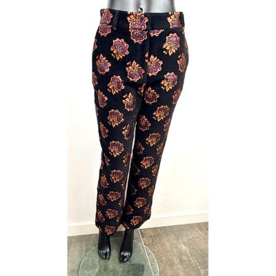 Le pantalon est noir et doré, avec un motif dessus.