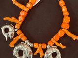 an orange bracelet with silver and coral beads on a black background