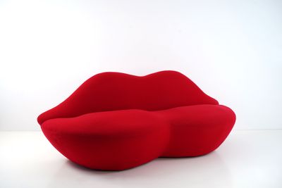 une image représentant un canapé rouge sur lequel est posée une lèvre rouge