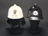 pair of white and black fireman ' s helmets on display on a black background