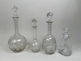 trois bouteilles en verre transparent et un bouchon en verre posés sur une surface blanche