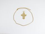 un collier en or orné d'une croix, posé sur une feuille de papier