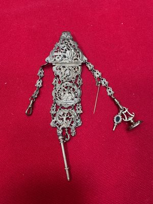an image of a silver broochle with a key attached to it