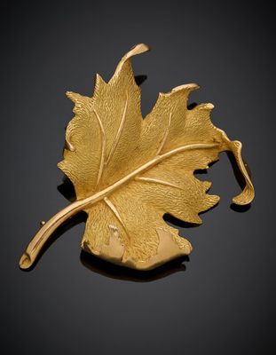 une image représentant une broche en feuille d'or posée sur une surface noire