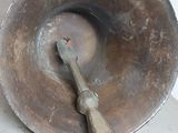 a large metal bowl with a wooden handle on the floor