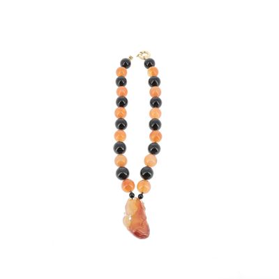 un gros plan sur un collier composé de perles orange et noires