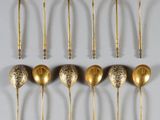 six gold spoons are lined up on a white surface