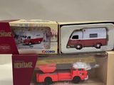 two red and white toy vehicles in boxes on a white surface