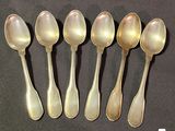 six silver spoons are lined up in a row on a black surface