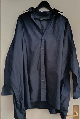 navy blue shirt hanging on a hanger in a white room