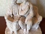 two figurines of two people sitting on a bench