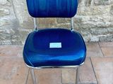 a blue chair with a label on it sitting on a tile floor