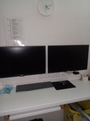 deux écrans d'ordinateur posés sur un bureau avec un clavier et une souris